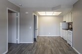 Located at 302 W G St in Ontario, California, this single-floor unit offers a functional and well-appointed layout. The main living area is finished with wood-style laminate flooring and features a wall-mounted air conditioning unit alongside a window that allows natural light to brighten the space. A skylight panel above the kitchen area further enhances the interior brightness.

The kitchen is efficiently designed and fully equipped with white cabinetry, a refrigerator, electric range, dishwasher, and a single-basin sink with a modern faucet. A range hood is mounted above the stove, and ample upper cabinet storage is provided throughout.

The bedroom is carpeted for comfort and is generously sized, featuring a window with views of the surrounding neighborhood. It connects directly to a walk-in closet with built-in shelving, offering excellent storage capacity.

The bathroom includes a vanity with dark countertop and a large mirror, alongside a combined tub and shower. The textured ceilings are consistent throughout the unit, contributing to its classic residential character. Overall, the space presents a clean, move-in-ready environment with practical finishes suited for comfortable everyday living.