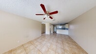 This single-story, 2-bedroom, 1-bathroom home offers a straightforward and functional layout across one level. The open living area is finished with large neutral ceramic tile flooring that extends throughout the home, creating a cohesive look. A textured ceiling and ceiling fan add practical character to the living space, which flows openly toward the kitchen.

The kitchen is equipped with white cabinetry, a peninsula-style breakfast bar with a laminate countertop, a white refrigerator, and a white electric range. A window above the sink allows natural light into the space. Notably, the kitchen also accommodates an in-unit washer and dryer, adding everyday convenience. A chandelier-style pendant light fixture enhances the dining area adjacent to the kitchen.

The bedrooms are comfortable in scale, each featuring tile flooring, a ceiling fan with light fixture, and a window that brings in natural light. The rooms offer a clean, neutral palette suitable for personalization.

The bathroom is finished with tile flooring, a soaking tub with white subway tile surround, a wall-mounted storage cabinet, and a vanity. The overall design of the home is simple and practical, offering a move-in-ready space with consistent finishes throughout.