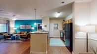 Located at 2000 Alexan Dr in Cary, NC, this single-floor residence offers a thoughtfully designed open-concept layout with warm hardwood flooring flowing throughout. The living room serves as a centerpiece, anchored by a striking teal accent wall, crown molding, a ceiling fan, and French doors that invite natural light and outdoor views. Adjacent to the living area, a dedicated dining space connects seamlessly to the kitchen, which features warm wood cabinetry, granite-style countertops, a tile backsplash, a full suite of black appliances, and a peninsula with pendant lighting overhead.

The residence includes multiple bedrooms, each with hardwood flooring and ceiling fans. The primary bedroom showcases a bold teal accent wall, ample natural light from large windows, and direct access to a bathroom with granite countertops and a walk-in closet. A secondary bedroom benefits from multiple windows with exterior views, and a third bedroom continues the cohesive design palette. The bathrooms feature warm wood vanities, granite countertops, and tiled tub-shower combinations. A secondary bathroom with convenient access to the dining area also includes a walk-in closet. This residence combines vibrant design details with practical, comfortable living spaces throughout.