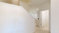 This two-story home is thoughtfully designed to maximize comfort and functionality across both floors. The main level features light-toned tile flooring throughout, creating a cohesive and clean aesthetic. The open-plan kitchen is a standout feature, boasting white shaker cabinetry, a center island with a built-in sink, stainless steel appliances, and pendant lighting that adds a modern touch. Recessed lighting further brightens the space. Adjacent to the kitchen, the dining area is bathed in natural light from large sliding glass doors fitted with vertical blinds, offering views of lush greenery outside. The living room continues this bright, airy feel with additional windows framing outdoor views. A staircase with white railings connects the two levels. Upstairs, the three bedrooms feature plush carpeting and ample natural light from well-positioned windows. The primary bedroom is a comfortable retreat, accompanied by a dedicated bathroom featuring a dual-sink vanity with a large mirror, generous cabinet storage, and a glass-enclosed walk-in shower. A second full bathroom on this level includes a tiled shower-tub combination. An additional closet provides practical storage. Throughout, the home maintains a clean, neutral palette of whites and warm beiges, lending a fresh and move-in-ready ambiance.