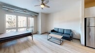 Located at 412 12th Ave SE in Minneapolis, MN, this efficiently designed studio presents a well-organized single-floor layout that maximizes every square foot. The open main living area features light hardwood-style flooring, neutral walls, and a ceiling fan, creating a bright and airy atmosphere. A large window floods the space with natural light and offers views of the surrounding neighborhood streetscape, while exposed ductwork along the ceiling adds an industrial touch to the modern aesthetic.

The kitchen runs along one wall in a galley-style configuration, outfitted with white shaker cabinetry, a white subway tile backsplash, light countertops, and a full suite of stainless steel appliances including a refrigerator, electric range, built-in microwave, and dishwasher. Under-cabinet lighting enhances both functionality and ambiance.

The bathroom features warm-toned ceramic tile flooring and wainscoting, a toilet, a vanity, and accessibility grab bars. A dedicated closet provides convenient storage, and an in-unit laundry area adds everyday practicality. Warm-toned wood doors at the entryway complement the overall modern, clean interior design of this thoughtfully laid-out studio.