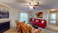This single-floor, 2-bedroom, 2-bathroom model offers a practical and comfortable layout designed to maximize livability. The living room serves as the heart of the unit, featuring plush carpeting, a ceiling fan with light fixture, a textured ceiling, and a sliding glass door that opens to a private balcony overlooking lush tree views, filling the space with natural light and greenery.

Adjacent to the living room is a defined dining area, set beneath a pendant chandelier and framed by chair-rail detailing, providing an intimate setting for meals. The galley-style kitchen is outfitted with warm wood cabinetry, white appliances including a range and refrigerator, a double sink, a dishwasher, and durable tile flooring.

Both bedrooms are generously sized with soft carpeting, large windows dressed with curtains, and ample closet space, creating restful retreats. The two full bathrooms each feature warm-toned tile flooring, wood vanity cabinetry with countertop sinks, and large mirrors. One bathroom includes a shower-tub combination. Neutral wall tones throughout contribute to the unit's bright, cohesive ambiance.