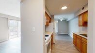 This single-floor unit offers a practical and cohesive layout finished with light wood-look flooring that runs consistently throughout the space, lending a clean, uniform aesthetic to every room. The galley-style kitchen is positioned along one side of the unit, featuring warm honey-toned wood cabinetry on both upper and lower levels, light countertops, and white appliances including a range and refrigerator. The kitchen opens directly into the living area, which benefits from a ceiling fan and neutral gray-toned walls that create a calm, understated atmosphere. A sliding door fitted with vertical blinds allows natural light to pour into the living space.

The two bedrooms are bright and simply appointed, each featuring windows with horizontal blinds that admit natural light. The neutral wall tones and light flooring keep the rooms feeling open and airy. The full bathroom includes a soaking tub with an integrated shower surround, chrome fixtures, and a grab bar, set against soft gray walls and matching wood-look flooring. The overall design of the unit is straightforward and functional, with a neutral color palette throughout that offers a versatile backdrop for a variety of interior styles.
