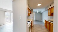 This single-floor unit offers a practical and cohesive layout finished with light wood-look flooring that runs consistently throughout the space, lending a clean, uniform aesthetic to every room. The galley-style kitchen is positioned along one side of the unit, featuring warm honey-toned wood cabinetry on both upper and lower levels, light countertops, and white appliances including a range and refrigerator. The kitchen opens directly into the living area, which benefits from a ceiling fan and neutral gray-toned walls that create a calm, understated atmosphere. A sliding door fitted with vertical blinds allows natural light to pour into the living space.

The two bedrooms are bright and simply appointed, each featuring windows with horizontal blinds that admit natural light. The neutral wall tones and light flooring keep the rooms feeling open and airy. The full bathroom includes a soaking tub with an integrated shower surround, chrome fixtures, and a grab bar, set against soft gray walls and matching wood-look flooring. The overall design of the unit is straightforward and functional, with a neutral color palette throughout that offers a versatile backdrop for a variety of interior styles.