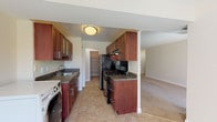 This single-floor residence offers a thoughtfully designed layout that balances functionality and comfort throughout its living spaces. The kitchen is a standout feature, showcasing rich dark wood cabinetry, granite countertops, and black stainless steel appliances including a gas range and refrigerator. A dedicated pantry with built-in shelving provides generous storage, while an in-unit washer is conveniently integrated into the kitchen area. The tile flooring adds durability and easy maintenance to this hardworking space.

The living area is generously sized and bathed in natural light, courtesy of large sliding glass doors fitted with vertical blinds that open to an outdoor view. An adjoining room with a window further enhances the sense of openness and connectivity throughout the main living space. Both areas feature neutral-toned carpet that extends a warm and inviting atmosphere.

The bedrooms are well-proportioned, carpeted, and finished in soft neutral tones, each offering ample wall space and closet storage with bifold doors. The bathroom is clean and functional, featuring a full soaking tub with tiled surround. Throughout the residence, consistent white trim, neutral walls, and practical finishes create a cohesive and move-in ready environment.