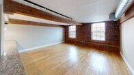 This 990 square foot apartment in Manchester, NH offers a perfect blend of modern amenities and industrial charm. The open-concept living area showcases exposed brick walls and rustic wooden beams, creating a warm and inviting atmosphere. Gleaming hardwood floors run throughout the main living spaces, while plush carpeting adds comfort to the bedrooms.

The kitchen is a highlight, featuring rich wooden cabinetry, sleek granite countertops, and stainless steel appliances. It's equipped with ample storage and counter space, making it ideal for cooking enthusiasts. The living room is spacious and bright, with large windows allowing natural light to flood the area.

Both bedrooms are generously sized, with the primary bedroom measuring 180 square feet. They feature neutral-toned walls, carpeted floors, and convenient closet space. The bathroom is modern and functional, with a stylish vanity and a combined washer and dryer unit for added convenience.

Additional features include exposed ductwork, adding to the industrial aesthetic, and strategic lighting throughout. The apartment's layout maximizes space efficiency, making it feel larger than its 990 square feet. Located at 195 McGregor St, A-111, this apartment offers a perfect balance of style, comfort, and practicality in the heart of Manchester.