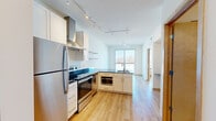 Located at 2905 Harriet Ave in Minneapolis, Minnesota, this one-bedroom, two-bathroom unit offers a well-designed, efficient layout with a modern aesthetic. Light hardwood flooring runs throughout the space, creating a warm and cohesive feel from room to room.

The open-concept kitchen is a standout feature, outfitted with stainless steel appliances including a refrigerator, electric range, microwave, and dishwasher. White cabinetry with dark countertops provides a clean, contemporary contrast, while a stainless steel ventilation hood and track lighting overhead add a polished touch. Open shelving and a peninsula with a sink enhance both functionality and style.

The living area flows naturally from the kitchen and receives generous natural light through large windows and a glass door that opens to a balcony, offering views of the surrounding Minneapolis neighborhood. The bedroom is a bright, cozy space with a large window showcasing outdoor views and an in-unit climate control unit. A closet and direct access to one of the two bathrooms add convenience.

Both bathrooms feature tile flooring, white vanity cabinetry with dark countertops, and clean, efficient layouts. Track lighting and mirrored vanities keep the spaces bright and functional. The unit's compact yet thoughtful design makes excellent use of every square foot.