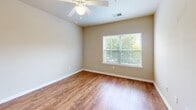 Located at 2401 Pamela Way in Blacksburg, Virginia, this one-bedroom, one-bathroom unit offers a well-organized single-floor layout designed for comfortable everyday living. The combined kitchen and living area forms the heart of the home, highlighted by warm hardwood-style flooring that extends throughout the main spaces. The kitchen is outfitted with rich, dark cabinetry, a peninsula island featuring a double-basin sink and granite-style countertops, and black appliances including a refrigerator, electric range, microwave, and dishwasher. A pendant light above the island and recessed ceiling lighting keep the space bright and functional. The bedroom is carpeted for comfort and features a ceiling fan, a large window that lets in generous natural light, and views of the surrounding community. Two closets provide ample storage, including a walk-in closet with built-in wire shelving. The full bathroom includes a single-sink vanity with a dark cabinet base, tile flooring, and a full-size tub-shower combination. Neutral warm beige tones are carried throughout the unit, creating a cohesive and inviting atmosphere. This thoughtfully laid-out residence offers practical amenities in a convenient Blacksburg location.