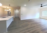This single-story home in Louisville, KY spans 1,200 square feet and features 4 bedrooms, 2 bathrooms, and a well-designed open-concept layout. Luxury vinyl plank flooring flows throughout, complemented by neutral-toned walls and clean white trim for a cohesive, modern aesthetic. The kitchen is a standout space, showcasing white shaker cabinetry with matte black hardware, a large center island with an undermount sink and white countertops, stainless steel appliances, and pendant globe lighting. It opens seamlessly into the living room, creating an ideal space for everyday living. The primary bedroom measures 180 square feet, offering ample space, while the three additional bedrooms feature large windows with blinds that allow natural light to fill each room. The primary bathroom includes a glass-enclosed walk-in shower, a wide vanity with white countertops, and wood-look flooring. The second bathroom features a tub/shower combo and a similar vanity setup. A dedicated laundry room houses a full-size washer and dryer and includes overhead shelving. Three hallways connect the layout efficiently, and the home's overall design emphasizes clean lines, functional spaces, and modern finishes throughout.