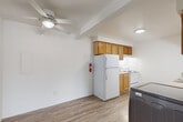 Located at 159 S Grove St in Ypsilanti, Michigan, this single-floor, one-bedroom, one-bathroom unit offers a well-organized layout across a comfortable footprint. The living room is bright and open, featuring soft carpeting, baseboard heating, a wall-mounted air conditioning unit, and a large window dressed with vertical blinds that allows generous natural light to fill the space. Adjacent to the living area, the dining room provides a dedicated space for meals and flows naturally into the kitchen. The kitchen is equipped with warm honey-toned wood cabinetry, a double-basin sink, white appliances including a refrigerator and electric range, and durable wood-look flooring. A ceiling fan with light fixture adds both comfort and functionality to the kitchen and dining area. The bedroom is a well-sized retreat with plush carpeting, a ceiling fan, baseboard heating, and direct access to a closet—two closets are included in the unit in total. The bathroom features tile flooring, a full-size tub and shower combo with white tile surround, and a vanity with storage. An in-unit washer and additional cabinetry are also present, enhancing everyday convenience. Warm wood-toned doors and trim carry a consistent, classic aesthetic throughout the home.