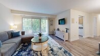 Located in the Village of Pine Court in Windsor Mill, Maryland, this single-floor residence offers two bedrooms, two bathrooms, and a well-organized layout designed for comfortable everyday living. The living room serves as the heart of the home, featuring hardwood-style flooring, neutral walls, and large sliding glass doors that flood the space with natural light and open onto a private balcony with lush tree views. A dedicated area accommodates dining just off the living space, completing an open, functional common area. The spacious primary bedroom offers a generous footprint with natural light from a large window, hardwood-style flooring, and direct access to a dedicated closet. The second bedroom is equally well-lit, with a window overlooking greenery and its own closet for ample storage. Each bathroom is distinctly appointed: one features a glass-enclosed shower, warm wood vanity cabinetry, white tile backsplash, and bright vanity lighting, while the second includes a full soaking tub with shower, wood cabinetry, and soft, neutral finishes throughout. Consistent hardwood-style flooring runs through the main living areas, tying the home together with a clean, cohesive aesthetic. The overall ambiance is bright, calm, and move-in ready.
