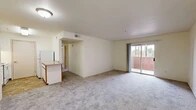 Located at 301 El Pueblo Rd NW in Los Ranchos de Albuquerque, New Mexico, this single-floor, 2-bedroom, 2-bathroom residence offers a well-organized and functional layout. The combined dining, kitchen, and living area forms the heart of the home, with soft carpet flooring throughout the living spaces and warm neutral walls creating a clean, inviting atmosphere. A sliding glass door in the living room opens to a private balcony, bringing in natural light and outdoor views. The kitchen features white cabinetry, under-cabinet lighting, and a peninsula counter that subtly defines the cooking space from the living area. Both bathrooms are finished with earthy stone-look tile flooring and include bathtub-shower combinations with built-in shelving. The two bedrooms are carpeted and offer a comfortable sense of space, with the primary bedroom being notably spacious. Natural light filters into the secondary bedroom through a window overlooking greenery. Three closets provide ample storage throughout the unit. A dedicated laundry room adds everyday convenience, while a hallway connects the private areas of the home seamlessly. The overall aesthetic is understated and move-in ready, suited for comfortable everyday living.