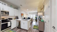 Located on Cheshire Bridge Road NE in Atlanta, Georgia, this one-bedroom, one-bathroom unit is thoughtfully designed to maximize every square foot of its compact footprint. The open-concept layout connects the kitchen and living room seamlessly, creating a cohesive and functional living space. The kitchen is outfitted with white shaker cabinetry, white quartz countertops, stainless steel appliances including a range, over-the-range microwave, refrigerator, and dishwasher, and a peninsula with bar seating — ideal for casual dining or meal prep. Crown molding and recessed lighting add a polished finish to the main living area, which is anchored by French doors that invite natural light and provide outdoor access. Wood-style plank flooring runs throughout, lending warmth and continuity across each room. The bedroom is a quiet, well-lit retreat featuring large windows with blinds and drapery, offering a comfortable and private atmosphere. The bathroom includes a combined tub and shower, a single vanity with a large mirror, and bright overhead lighting. A hallway connects the bedroom and bathroom efficiently. Overall, the unit presents a clean, modern aesthetic well-suited for everyday living in the heart of Atlanta.