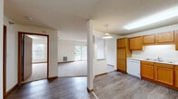 Located at 3533 Willow Ave in White Bear Lake, Minnesota, this one-bedroom, one-bathroom unit offers a practical and comfortable layout across a single floor. The open-concept kitchen and living area creates a seamless flow, with the kitchen featuring warm oak cabinetry, ample upper and lower storage, white appliances including a dishwasher, electric range, microwave, and refrigerator, plus a double basin sink and durable hardwood-style vinyl flooring. A pendant light fixture above the kitchen peninsula adds a functional accent. The living room is carpeted and bathed in natural light, with sliding glass doors opening to a private balcony overlooking greenery — an inviting outdoor extension of the living space. A structural column subtly defines the transition between kitchen and living areas. The spacious bedroom features plush carpet, a large window for natural light, and a closet with a wood-toned door. The full bathroom includes a single-sink vanity with oak cabinetry, a tub/shower combination, and wood-style flooring. A dedicated in-unit laundry space houses a full-size washer and dryer with wire shelving above for added storage. Textured ceilings and warm wood trim are consistent throughout, giving the unit a cohesive, classic aesthetic.