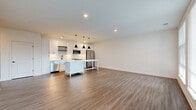 Located at 1350 W Fifth Ave in Columbus, Ohio, this thoughtfully designed 2-bedroom, 2-bathroom residence offers a clean, modern aesthetic with consistent wood-look flooring and crisp white walls throughout. The open-concept kitchen and living area serves as the heart of the home, showcasing white shaker cabinetry, a full suite of stainless steel appliances, a subway tile backsplash, and a large central island with a white countertop illuminated by a trio of sleek black pendant lights. The spacious living area flows naturally from the kitchen, bathed in natural light from large windows. Both bedrooms are generously sized with the primary bedroom offering direct access to a private en-suite bathroom, while a well-appointed walk-in closet with full wire shelving systems provides ample storage. The bathrooms feature white vanities with black hardware accents and tiled tub-shower combinations. A private balcony extends the living space outdoors, offering open views of the Columbus skyline and surrounding neighborhood. Additional conveniences include a dedicated laundry area, utility room, and multiple closets. The consistent use of neutral tones and modern fixtures creates a bright, cohesive, and move-in-ready living environment.