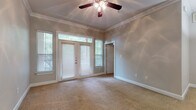 This single-story space is thoughtfully designed with a cohesive blend of classic and contemporary finishes throughout. The main living area is generously proportioned, finished with plush neutral carpeting and accented by elegant crown molding that runs along the ceiling perimeter. A ceiling fan with a light fixture anchors the room, while a set of French doors flanked by windows invites natural light and provides views of the surrounding greenery. The open layout connects seamlessly to the kitchen, which features a U-shaped configuration with rich, dark cabinetry, granite-look countertops, a stainless steel dishwasher, and hardwood-style flooring that adds warmth and contrast to the bold cabinetry.

The bedroom is a comfortable, carpeted retreat with crown molding and mirrored sliding closet doors that enhance the sense of space. The full bathroom is well-appointed, offering dark espresso-toned vanity cabinetry, a wide illuminated mirror, a soaking tub with shower, and hardwood-style flooring that ties the room together. Throughout the space, clean white trim, neutral wall tones, and consistent finishes create a polished and unified aesthetic.