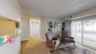 Located at 100 Piccadilly Loop in Yorktown, Virginia, this single-floor, 2-bedroom, 2-bathroom home offers a practical and comfortable layout. The open-concept living, dining, and kitchen area forms the heart of the home, where carpet flooring in the living space transitions to wood-look flooring in the kitchen. A pass-through window connects the kitchen to the living area, enhancing the open feel. The kitchen features white shaker-style cabinetry, granite-look countertops, stainless steel appliances including a refrigerator, range, and dishwasher, and light wood-look flooring. The living room is bright and welcoming, with a sliding glass door that opens to a patio and allows natural light to fill the space. A ceiling fan is positioned in the dining area for added comfort. Both bedrooms feature carpet flooring and windows with blinds that offer views of surrounding greenery. Each bedroom includes closet storage, and the primary bedroom is comfortably sized. The two bathrooms are clean and functional, each featuring a tub-shower combination and wood-look tile flooring. A dedicated in-unit laundry area with wire shelving above provides added convenience. Three closets and a hallway complete this well-organized, efficient floor plan.