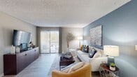 This well-appointed single-floor residence offers a thoughtfully designed layout that balances comfort and modern style throughout. The living room serves as the heart of the home, featuring light wood-look flooring, a textured ceiling, and a striking blue accent wall adorned with contemporary artwork. The space is bright and welcoming, with a sliding glass door providing direct access to a private outdoor area and filling the room with natural light. The open flow connects the living area seamlessly to a dedicated dining space, creating an ideal setting for both relaxing and entertaining. The kitchen is efficiently laid out with white cabinetry accented by gold hardware, granite countertops, a classic subway tile backsplash, and stainless steel appliances. In-unit laundry is also conveniently integrated into this space. The bedroom is a tranquil retreat highlighted by a bold blue accent wall, plush carpeting, and a natural window view, complemented by a walk-in closet offering generous storage. The bathroom features granite countertops, white cabinetry with gold hardware, and a tiled shower-tub combination. Throughout the residence, a cohesive blue and neutral color palette ties each room together, creating a harmonious and inviting atmosphere.