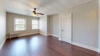Located at 105 Ward Parkway in Kansas City's desirable Ward Parkway corridor, this two-bedroom, two-bathroom residence offers a thoughtfully arranged single-floor layout. The living room is a welcoming centerpiece, featuring rich hardwood flooring, a ceiling fan with light fixture, and elegant arched doorways that lend a classic architectural character to the space. The kitchen is efficiently designed with warm oak cabinetry, white countertops, stainless steel appliances including a gas range and refrigerator, and tile flooring. The primary bedroom offers generous proportions with hardwood floors, a ceiling fan, natural light from multiple windows, and a classic radiator for supplemental heating. The second bedroom is carpeted and features a ceiling fan, a large sliding-door closet, and a window with natural light. Both bathrooms maintain a clean, classic aesthetic with white tile, a vanity, and a bathtub/shower combo, each enhanced by windows that bring in natural light. Arched passageways throughout the hallways add architectural charm, while ceiling fans in each main room ensure year-round comfort. The layout flows naturally between rooms, creating a cohesive and functional living environment.