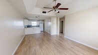 Unit 4 is a well-laid-out 2-bedroom, 1-bathroom residence that offers a practical and comfortable living environment across a single floor. Light-toned wood-style flooring runs consistently throughout the unit, lending a clean and cohesive look to every room. Textured ceilings are present throughout, and ceiling fans are installed in the living room and both bedrooms, providing both airflow and ambient lighting.

The combined kitchen and living room area forms the heart of the unit. The kitchen features white cabinetry with decorative hardware, gray laminate countertops, a white electric range, a double-basin sink, and a refrigerator. A peninsula provides additional counter space and creates a natural transition into the dining and living areas. A pendant chandelier illuminates the kitchen, while a window allows in natural light.

The living room is open and airy, featuring a window with blinds that brings in natural light, a ceiling fan, and direct access to the unit's entry door. A hallway connects the living area to the two bedrooms and bathroom.

Both bedrooms are comfortably sized, each featuring a ceiling fan, a window with blinds for natural light, and neutral beige walls. The primary bedroom includes access to a closet. The bathroom is equipped with a tiled tub-shower combination, a toilet, and white cabinetry for storage.