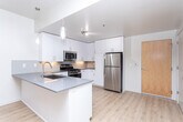Located at 122 E Sego Lily Dr in Sandy, UT, this well-appointed 2-bedroom, 2-bathroom residence offers a thoughtfully designed single-level floor plan. The open-concept kitchen and living area serves as the heart of the home, featuring white shaker cabinetry extending to the ceiling, a subway tile backsplash, dark countertops, and a full suite of stainless steel appliances including a gas range, microwave, dishwasher, and refrigerator. A peninsula with pendant lighting provides additional prep space and connects seamlessly to the living room. Light wood-style flooring flows throughout the main living areas, complemented by a sliding glass door in the living room that invites natural light and outdoor views. The generously sized primary bedroom offers plush carpeting, ample natural light, and access to a large walk-in closet with wire shelving on multiple walls. The second bedroom is equally well-lit with its own walk-in closet. Both bathrooms are finished with clean, modern details, including subway-tiled tub-shower surrounds, dark countertops, and wood-style flooring. The overall aesthetic is bright, clean, and contemporary throughout.