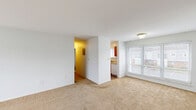 Located at 1 Pine Tree Boulevard in Old Bridge, NJ, this single-floor, one-bedroom, one-bathroom home offers a practical and well-organized layout. The combined living and dining area is the heart of the space, featuring wall-to-wall carpet, bright white walls, and a large sliding window that invites ample natural light and outdoor views of the surrounding neighborhood. A secondary window along an adjacent wall further enhances the open, airy feel of this central living space. The entry door is positioned in the living area and includes overhead ventilation, keeping the space comfortable year-round. The kitchen is efficiently arranged in a galley style, with warm honey-toned wood cabinetry lining both sides, light countertops, tile flooring, and a range with overhead ventilation — providing ample storage and workspace for everyday cooking. The bedroom is generously sized, featuring carpeted flooring, soft neutral walls, a bright window with blinds, and a double sliding-door closet offering substantial storage. A hallway connecting the main rooms includes an additional closet for extra organization. The bathroom is clean and functional, finished with white subway-style wall tiles and a full tub-shower combination with a window for ventilation.