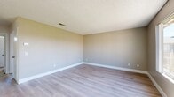 This single-floor, 2-bedroom, 2-bathroom home in Hesperia, CA offers a clean and functional layout designed for comfortable everyday living. The combined kitchen and living room serves as the heart of the home, featuring light-toned luxury vinyl plank flooring, white cabinetry with dark hardware, dark countertops, and black appliances including a dishwasher and gas range. A ceiling fan with lighting anchors the space, while a sliding glass door and large window allow generous natural light and views of the surrounding greenery. A peninsula counter provides additional workspace and a natural division between the kitchen and living areas. The living room benefits from a large sliding window that frames outdoor views and fills the room with sunlight. The primary bedroom is spacious and finished with warm neutral-toned walls, textured ceilings, and light LVP flooring. The secondary bedroom is carpeted and includes a window with vertical blinds offering outdoor views. Both bathrooms are clean and simply appointed, with light flooring and white fixtures. A hallway connects the bedrooms and bathrooms, providing a well-organized flow throughout the home. Textured ceilings are consistent across all rooms, contributing to the home's cohesive and practical design.