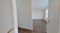 This well-designed two-story home offers 3 bedrooms and 2 bathrooms across two thoughtfully laid-out floors. The main level features an open-concept kitchen and living area with dark hardwood-style flooring that runs consistently throughout the home. The kitchen is a standout, boasting white shaker cabinetry, quartz countertops, a large center island with a built-in sink, stainless steel appliances, a decorative tile backsplash, and pendant lighting above the island. The living area flows naturally from the kitchen and is brightened by natural light from large windows fitted with horizontal blinds. Ceiling fans are present in the living area and bedrooms for added comfort. The spacious primary bedroom features generous closet space with a well-organized walk-in closet equipped with built-in shelving and hanging rods. The primary bathroom offers a dual-sink vanity with white cabinetry, a large mirror, and a tiled walk-in shower. The secondary bathroom includes a soaking tub with marble-style tile surround, a single-sink vanity, and a toilet. Additional bedrooms are bright and well-proportioned, each with windows allowing natural light. The home's clean, neutral palette and modern finishes create a cohesive and move-in-ready living environment.