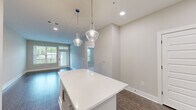 Located in Johns Creek, GA, this well-appointed one-bedroom, one-bathroom residence offers a thoughtfully designed layout with modern finishes throughout. The open-concept kitchen and living area serves as the heart of the home, highlighted by rich dark hardwood-style flooring, recessed lighting, and a striking white kitchen island with built-in shelving, illuminated by elegant glass pendant lights. The kitchen is fully equipped with stainless steel appliances including a gas range, microwave, refrigerator, and dishwasher, complemented by crisp white subway tile backsplash, granite countertops, and gray shaker-style cabinetry. The living area is bright and airy, featuring a glass-paneled door and large windows that invite abundant natural light and outdoor views. The bedroom is carpeted for comfort, complete with a ceiling fan and a generous window with garden views. The bathroom features large-format tile flooring, a glass-enclosed walk-in shower with tile surround, granite vanity, and built-in open shelving. A dedicated closet and hallway complete the functional floor plan. The overall ambiance is clean, contemporary, and move-in ready, reflecting a cohesive neutral palette and quality craftsmanship throughout.