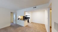 This single-story unit on Northcliffe Drive in Winston-Salem, North Carolina offers a practical and comfortable layout with clearly defined living spaces. The living room is generously proportioned, featuring plush wall-to-wall carpeting, a textured ceiling, and a corner fireplace that serves as a focal point. A large window allows natural light to fill the room while providing a view of the surrounding greenery outside.

The kitchen is designed in a galley style with wood-look flooring, white cabinetry, and dark granite-style countertops that extend to a pass-through breakfast bar separating the kitchen from the adjoining dining and living areas. Black appliances, including a refrigerator and an electric range with overhead ventilation, are integrated throughout. A pantry or storage closet at the end of the kitchen adds additional functionality.

The bedroom is a well-sized, carpeted room with a large window that brings in natural light. Two full bathrooms are present in the unit, each featuring a tub-shower combination, a single vanity with dark countertops, white cabinetry, wood-look flooring, and brushed nickel fixtures. The overall aesthetic is clean and neutral, creating a move-in-ready environment.
