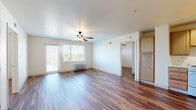 Located at 1700 Pierce St in Lakewood, Colorado, this two-bedroom, one-bathroom residence offers a practical and comfortable single-floor layout. Warm hardwood-style flooring runs consistently throughout the unit, lending a cohesive and inviting feel to every room.

The combined kitchen and living area forms the heart of the home. The kitchen is equipped with oak-toned cabinetry, white appliances including a range, dishwasher, and refrigerator, along with track lighting overhead and ample counter space. The living area benefits from large windows and a sliding glass door that opens to a balcony, filling the space with natural light and offering open outdoor views of the surrounding Lakewood neighborhood.

Both bedrooms are well-proportioned and feature ceiling fans with light fixtures, baseboard heating, and window blinds. One bedroom includes a spacious walk-in closet with built-in shelving and hanging rods, providing generous storage. The second bedroom offers a sliding-door closet.

The bathroom is designed with accessibility in mind, featuring grab bars, a roll-in shower, and hardwood-style flooring that continues from the rest of the unit. An additional closet with open shelving is conveniently located just outside the bathroom. The unit also includes a wall-mounted HVAC unit in the living area for year-round climate control.