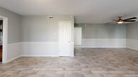 Located on Cedar Springs Road in Dallas, TX, this single-story 2-bedroom, 2-bathroom home offers a practical and comfortable layout. Light-toned wood-look tile flooring flows consistently throughout the main living areas and bedrooms, creating a cohesive and easy-to-maintain interior. The open living room is well-lit by natural light through blinds-fitted windows and features a ceiling fan overhead, while a half-wall divider subtly defines the transition toward the rest of the home. The kitchen is equipped with rich dark wood cabinetry, a metallic diamond-pattern tile backsplash, granite-style countertops, a stainless steel dishwasher, and a stainless steel range with microwave above — alongside a separate entry door with adjacent window that allows additional natural light. Both bedrooms are generously proportioned, each featuring ceiling fans and neutral gray walls. The spacious primary bedroom offers ample room for furnishings. The two bathrooms are tiled with bold diagonal-pattern stonework; one includes a tub-shower combo with sliding glass doors, while the other features a walk-in shower enclosure with sliding glass panels and a built-in niche. A connecting hallway with stone-look tile links the main areas of the home efficiently.