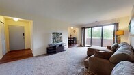 Located at 16 Brandywine in Amherst, Massachusetts, this single-floor unit at Brandywine Apartments offers a well-organized layout designed for comfortable everyday living. The carpeted living room serves as the central gathering space, featuring a large sliding glass door that opens onto a private balcony with lush, tree-lined views, filling the room with natural light. The open connection between the living room and dining area creates a seamless flow for entertaining and daily use. The dining area features rich hardwood-style flooring and a window that further enhances the sense of openness. The galley-style kitchen is efficiently designed with wood-tone cabinetry, white appliances including a gas range, ample counter space, and direct access to the dining area. Two carpeted bedrooms each offer generous closet space with bi-fold doors, providing practical storage solutions. The full bathroom is equipped with a tub-shower combination and a wood-accented vanity with a built-in sink. Throughout the unit, neutral wall tones and consistent finishes contribute to a clean, cohesive aesthetic. The balcony access and surrounding greenery make this a notably serene residential setting within close proximity to the University of Massachusetts Amherst campus.