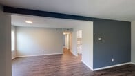 Located at 2007 Morningside Dr in Burlington, NC, this single-story home presents a clean, updated interior with a cohesive neutral color palette throughout. The living area is a standout space, featuring rich, dark-toned hardwood-style flooring and a bold navy accent wall that adds visual contrast against the light gray surroundings. A set of French doors and multiple windows allow natural light to fill the room, creating a bright and open atmosphere. The layout flows naturally from the living area toward the kitchen and bedrooms, aided by an open-concept design with a defining structural column.

The kitchen is well-appointed with white cabinetry, granite-look countertops, stainless steel appliances including a refrigerator, range, and dishwasher, and light hardwood-style flooring. A closet pantry provides additional storage.

The bedrooms are carpeted in gray, offering a soft, comfortable surface underfoot. Each room includes a ceiling fan with light fixture and a window fitted with blinds, ensuring both ventilation and natural light. The bathroom features wood-style flooring, a granite-topped vanity with white cabinetry, and a tub-shower combination, maintaining the home's consistent, updated aesthetic throughout.