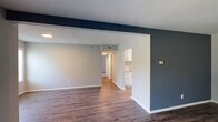 Located at 2007 Morningside Dr in Burlington, NC, this single-story home presents a clean, updated interior with a cohesive neutral color palette throughout. The living area is a standout space, featuring rich, dark-toned hardwood-style flooring and a bold navy accent wall that adds visual contrast against the light gray surroundings. A set of French doors and multiple windows allow natural light to fill the room, creating a bright and open atmosphere. The layout flows naturally from the living area toward the kitchen and bedrooms, aided by an open-concept design with a defining structural column.

The kitchen is well-appointed with white cabinetry, granite-look countertops, stainless steel appliances including a refrigerator, range, and dishwasher, and light hardwood-style flooring. A closet pantry provides additional storage.

The bedrooms are carpeted in gray, offering a soft, comfortable surface underfoot. Each room includes a ceiling fan with light fixture and a window fitted with blinds, ensuring both ventilation and natural light. The bathroom features wood-style flooring, a granite-topped vanity with white cabinetry, and a tub-shower combination, maintaining the home's consistent, updated aesthetic throughout.