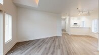 Located at 2226 Elliott Ave in Seattle's vibrant Belltown neighborhood, this two-bedroom, two-bathroom residence offers a thoughtfully designed single-level layout with a clean, modern aesthetic. Light-toned hardwood-style flooring flows consistently throughout, complementing crisp white walls and bright, airy interiors.

The open-concept living and dining area serves as the heart of the home, anchored by a fireplace and bathed in natural light from multiple windows. A balcony extends the living space outdoors, offering views of the surrounding Seattle cityscape. The kitchen features white cabinetry and seamlessly connects to the main living area.

The primary bedroom is a well-proportioned retreat with multiple windows framing city views, a ceiling fan, and baseboard heating. The second bedroom mirrors this comfort with a bay-style window arrangement, ceiling fan, and ample closet space including sliding-door closets. Six closets total throughout the residence provide exceptional storage.

Both bathrooms are finished with white vanities, white quartz countertops, and hardwood-style flooring. One bathroom features a soaking tub with tiled surround and a window with city views. A dedicated in-unit laundry room with wire shelving adds everyday convenience. A welcoming entrance and central hallway complete this well-appointed Seattle residence.