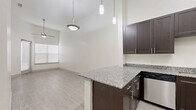 Located at 4520 Gus Thomasson Rd in Mesquite, TX, this one-bedroom, one-bathroom unit offers a well-designed single-floor layout with thoughtful modern finishes. The kitchen is a standout feature, boasting rich dark cabinetry, granite countertops, and a full suite of stainless steel appliances including a refrigerator, electric range, built-in microwave, and dishwasher. Light wood-look flooring flows through the main living areas, complementing the bright, white walls and creating a clean, contemporary feel. The living area benefits from a ceiling fan and access to natural light through blinded windows. The bedroom is a comfortable retreat featuring plush carpeting, soaring vaulted ceilings, a ceiling fan, and a window that fills the room with natural light. It connects directly to a dedicated closet with built-in shelving and a well-appointed bathroom. The bathroom features tile flooring, a dark vanity with a granite countertop, and a glass-enclosed walk-in shower with white subway tile surround and a built-in tub. High ceilings are a consistent architectural element throughout the unit, enhancing the overall sense of openness and volume within this efficiently designed space.