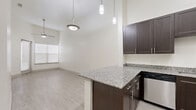 Located at 4520 Gus Thomasson Rd in Mesquite, TX, this one-bedroom, one-bathroom unit offers a well-designed single-floor layout with thoughtful modern finishes. The kitchen is a standout feature, boasting rich dark cabinetry, granite countertops, and a full suite of stainless steel appliances including a refrigerator, electric range, built-in microwave, and dishwasher. Light wood-look flooring flows through the main living areas, complementing the bright, white walls and creating a clean, contemporary feel. The living area benefits from a ceiling fan and access to natural light through blinded windows. The bedroom is a comfortable retreat featuring plush carpeting, soaring vaulted ceilings, a ceiling fan, and a window that fills the room with natural light. It connects directly to a dedicated closet with built-in shelving and a well-appointed bathroom. The bathroom features tile flooring, a dark vanity with a granite countertop, and a glass-enclosed walk-in shower with white subway tile surround and a built-in tub. High ceilings are a consistent architectural element throughout the unit, enhancing the overall sense of openness and volume within this efficiently designed space.