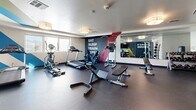 Located at 521 W Colorado St in Glendale, California, this fitness center is a thoughtfully designed exercise space that delivers a comprehensive workout environment on a single floor. The room features durable rubber flooring throughout, providing a safe and practical surface suited for a wide range of physical activities.

The space is outfitted with an impressive array of equipment, including multiple treadmills, an elliptical trainer, a rowing machine, and a multi-station cable machine with TRX suspension training capabilities. Strength training is well-supported with adjustable workout benches, a dumbbell rack, medicine balls, and an Everlast punching bag with stand. A dedicated small-accessories shelf keeps resistance bands, foam rollers, and similar items organized and accessible.

Aesthetically, the fitness center stands out with bold, energizing design elements. Geometric color-block murals in blue, green, and red accent the walls, while motivational phrases — "Eat Sleep Train Repeat" and "Impossible Is Nothing" — are prominently displayed as wall graphics, reinforcing an athletic atmosphere. Flush-mounted drum pendant lights provide consistent, even illumination throughout the space. Windows along the perimeter allow natural light to filter in. A wall-mounted flat-screen TV and a stainless steel water station round out the amenities, making this a fully functional and inviting fitness facility.