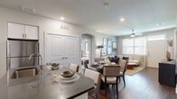 This single-story, 2-bedroom, 2-bathroom residence offers a thoughtfully designed open-concept layout that seamlessly connects the kitchen, dining, and living areas. The kitchen is outfitted with white shaker-style cabinetry, dark countertops, a subway tile backsplash, and a full suite of stainless steel appliances, including a dishwasher, range, and microwave. A kitchen island provides additional prep and counter space. Rich hardwood-style flooring runs throughout the main living areas, complementing the neutral, light-toned walls.

The dining area sits at the heart of the home, framed by an elegant arched doorway that leads to the bedrooms. The living room is bright and welcoming, featuring a ceiling fan, large windows with natural light, and direct access to the front entry. Both bedrooms are carpeted and include ceiling fans and ample natural light. The primary bedroom features a dedicated ensuite bathroom with dark countertops, white cabinetry, and a spacious walk-in closet with built-in shelving and hanging rods. A second well-sized closet and full bathroom serve the additional bedroom. The overall ambiance is modern, clean, and comfortable throughout.