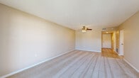 Located at 6551 Gulf Gate Place in Sarasota, FL, this single-floor, 3-bedroom, 1-bathroom home offers a practical and well-organized layout. The living room serves as the central gathering space, featuring plush wall-to-wall carpeting, warm neutral tones, a ceiling fan with light fixture, and a sliding glass door that fills the room with natural light and provides outdoor access. The layout flows through two hallways connecting the bedrooms and shared spaces, with a transition from carpet to tile flooring in the common areas. Each of the three bedrooms is carpeted and features louvered bifold closet doors offering ample storage; several bedrooms include windows with vertical blinds that allow natural light while maintaining privacy. The primary bedroom is a comfortable size with its own closet and direct hallway access. The kitchen is finished with light tile flooring, white cabinetry, and a stainless steel refrigerator, with a window providing natural ventilation. The bathroom features tile flooring, a warm-toned wood vanity with a white countertop, and a tub/shower combination with full tile surround. Overall, the home presents a clean, neutral palette suited for easy personalization.