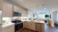 This single-floor residence at Sutton Landing at Uniondale, located at 2000 Sutton Court in Uniondale, New York, offers a thoughtfully designed living space with contemporary finishes and a cohesive aesthetic throughout.

The open-concept kitchen is a standout feature, equipped with stainless steel appliances including an electric range, built-in microwave, refrigerator, and dishwasher. Light wood-toned cabinetry pairs with bright white quartz countertops and a classic subway tile backsplash. A peninsula with an undermount sink and pendant lighting above creates a natural transition into the living area, enhancing the sense of openness and flow.

The living room receives abundant natural light through large windows dressed with sheer white curtains. Rich hardwood-style flooring runs throughout the main living areas, adding warmth and continuity. Recessed lighting complements the overall bright, airy atmosphere.

The bedroom is a calm retreat, featuring the same hardwood-style flooring, a generously sized window with natural light, and neutral wall tones that create a peaceful environment.

The bathroom is finished with large-format marble-look tile flooring, a modern vanity with clean white cabinetry, a frameless glass shower enclosure, and bright vanity lighting, delivering a polished, spa-inspired feel.