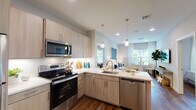 This single-floor residence at Sutton Landing at Uniondale, located at 2000 Sutton Court in Uniondale, New York, offers a thoughtfully designed living space with contemporary finishes and a cohesive aesthetic throughout.

The open-concept kitchen is a standout feature, equipped with stainless steel appliances including an electric range, built-in microwave, refrigerator, and dishwasher. Light wood-toned cabinetry pairs with bright white quartz countertops and a classic subway tile backsplash. A peninsula with an undermount sink and pendant lighting above creates a natural transition into the living area, enhancing the sense of openness and flow.

The living room receives abundant natural light through large windows dressed with sheer white curtains. Rich hardwood-style flooring runs throughout the main living areas, adding warmth and continuity. Recessed lighting complements the overall bright, airy atmosphere.

The bedroom is a calm retreat, featuring the same hardwood-style flooring, a generously sized window with natural light, and neutral wall tones that create a peaceful environment.

The bathroom is finished with large-format marble-look tile flooring, a modern vanity with clean white cabinetry, a frameless glass shower enclosure, and bright vanity lighting, delivering a polished, spa-inspired feel.