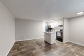 Located at 1054 S Dahlia St in Glendale, Colorado, this one-bedroom, one-bathroom unit offers a well-planned single-floor layout designed to maximize every inch of its compact footprint. The open-concept living and kitchen area is anchored by rich, dark hardwood-style plank flooring that runs throughout, creating a warm and cohesive aesthetic. Neutral gray walls and a textured ceiling complement the bright, clean finish of the space.

The kitchen is a functional highlight, featuring white cabinetry, a white peninsula that provides additional prep and dining space, a black refrigerator, and a black range — offering a modern contrast against the light cabinetry. A window near the entry brings in natural light and is paired with a wall-mounted HVAC unit and baseboard heating.

The bedroom is a comfortable retreat with soft wall-to-wall carpeting, a window with blinds offering outdoor views, a closet with white panel doors, and a textured ceiling with overhead lighting. The room provides a quiet, private atmosphere well-separated from the main living area.

The bathroom is clean and bright, finished with full white subway tile surrounding a full-length soaking tub, a large mirror, and a window that introduces natural light. The overall design throughout the unit is consistent, practical, and move-in ready.