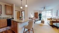 Located at 2911 Blue Aster Blvd in Sun Prairie, Wisconsin, this single-floor residence offers a well-designed, open-concept layout with warm finishes throughout. The kitchen is a standout feature, showcasing rich honey-toned cabinetry, granite countertops, hardwood-style flooring, and black appliances including a refrigerator, range, microwave, and dishwasher. A peninsula with pendant lighting overhead provides casual seating and serves as a natural transition into the living and dining area. The living room is bright and welcoming, with carpet flooring, a ceiling fan, and a large sliding glass door that invites natural light and provides outdoor views. The bedroom is generously sized with plush carpet, multiple windows for natural light, and a walk-in closet offering ample storage. The bathroom features granite countertops, warm wood cabinetry, hardwood-style flooring, and a shower-tub combination. Conveniently, in-unit laundry is located just off the bathroom. Neutral wall tones and consistent warm wood accents throughout the space create a cohesive and comfortable ambiance, making this Sun Prairie residence a practical and inviting place to call home.