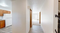Located in Grand Rapids, Michigan, this tri-level home at 1359 Dewberry Pl NE offers a well-distributed layout across three floors plus a basement. The main level features a bright hallway with light hardwood-style flooring that leads to the living room, which is highlighted by a large sliding glass door with vertical blinds, flooding the space with natural light and providing views of the lush outdoor greenery. The kitchen is equipped with warm-toned wood cabinetry, granite-look countertops, a double-basin sink, a dishwasher, and an electric range, with a window overlooking the outdoors. Both bathrooms are functional and clean, with one featuring wood-look tile flooring, a warm-toned vanity, and a full tub-shower combination. The two bedrooms are carpeted and generously sized — the primary bedroom offers ample room with closet access and natural light from a dedicated window. Additional rooms include a second carpeted bedroom with multiple doorways. The unfinished basement provides notable storage and utility potential, with exposed wood-beam ceilings, concrete floors, and visible electrical panel access. Textured ceilings and warm wood-trimmed interior doors are consistent design elements throughout the home.