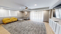 Located at 1515 Penn Ave in Wilkinsburg, PA, this thoughtfully designed single-floor space offers a seamless blend of functionality and modern aesthetics. The open-concept layout combines a fully equipped kitchen and a spacious living area, making it well-suited for gatherings and communal use.

The living area is bright and welcoming, featuring large windows with sheer curtains and vertical blinds that allow generous natural light to filter in. A ceiling fan with integrated lighting adds both comfort and style. The space is anchored by a large area rug and includes a built-in storage credenza topped with a wall-mounted flat-screen television, providing a polished focal point.

The kitchen is outfitted with stainless steel appliances, including a French door refrigerator, microwave, and range. Crisp white cabinetry lines the walls, offering ample storage, while light hardwood flooring runs throughout. A long, solid wood dining table with leather-upholstered chairs serves as a central gathering point, complemented by additional folding table space.

Outside, a spacious paved patio enclosed by a horizontal wood privacy fence provides an inviting outdoor area complete with a picnic table and grill, surrounded by mature trees. The overall ambiance of this space is clean, contemporary, and highly functional.