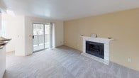 Located at 32905 19th Pl S, Unit 302, in Federal Way, Washington, this single-floor residential unit offers a thoughtfully laid-out interior designed for comfortable everyday living. The spacious living room serves as the heart of the home, anchored by a tile-surround wood-burning fireplace and a warm accent wall. A sliding glass door opens to a private balcony, filling the room with natural light and offering outdoor views. Soft carpeting throughout the living and bedroom areas adds warmth and comfort underfoot. The galley-style kitchen is efficiently designed with abundant white cabinetry, a full suite of white appliances including a refrigerator, electric range, microwave, and dishwasher, and a pass-through window connecting to the living area. Light tile flooring and a skylight-style ceiling fixture keep the kitchen bright and functional. Two well-proportioned bedrooms each feature plush carpeting, large windows that invite natural light and greenery views, and baseboard heating for year-round comfort. A dedicated in-unit laundry area with a full-size washer and dryer adds significant convenience. The overall palette is clean and neutral, creating a bright, move-in-ready atmosphere throughout.