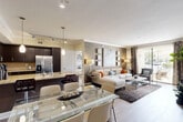 Located in Miami Lakes, FL, this well-appointed 1-bedroom, 2-bathroom residence offers a thoughtfully designed single-floor layout that maximizes both comfort and functionality. The open-concept living area seamlessly connects the kitchen, dining, and living spaces, creating an inviting and airy atmosphere. The kitchen is a standout feature, equipped with dark espresso cabinetry, granite countertops, a large center island with a double sink, stainless steel appliances including a double oven, and pendant lighting that adds a refined touch. Crown molding and track lighting enhance the overall aesthetic. The living room is anchored by a textured accent wall, large-format artwork, and floor-to-ceiling sliding glass doors that open to a private balcony, filling the space with natural light and offering pleasant outdoor views. The spacious primary bedroom features plush carpeting, a ceiling fan, a walk-in closet, and a serene, neutral palette. Both bathrooms are finished with granite vanity tops, dark cabinetry, large framed mirrors, and tile flooring — one with a soaking tub and the other with a glass-enclosed shower. A dedicated laundry area and hallway closet provide practical storage solutions throughout the home.
