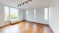 Located at 4240 Chestnut Street in Philadelphia's University City neighborhood, this single-floor, 3-bedroom, 2-bathroom unit offers a clean, modern design with consistent hardwood-style flooring throughout. The open-concept kitchen and living area serves as the heart of the home, anchored by a large central island with a white quartz countertop, stainless steel sink, and pendant lighting. The kitchen is equipped with stainless steel appliances including a gas range, microwave, and refrigerator, complemented by a mix of white upper cabinetry and natural wood-toned lower cabinets. A tall, narrow window allows natural light to brighten the space. The living area features track lighting and vertical windows that offer views of the surrounding neighborhood. The primary bedroom is a well-proportioned room with large windows and a dedicated closet with wire shelving. The additional bedrooms are bright and functional, each with hardwood-style flooring. The two bathrooms are finished in a clean, minimal aesthetic — one features a walk-in shower with white subway tile and a grab bar, while the other includes a full soaking tub and a single vanity with light wood cabinetry. Crisp white walls and modern fixtures unify the overall design throughout.